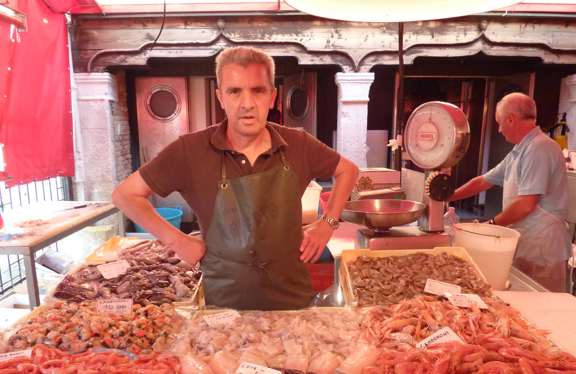 Vendor standing at a fish stall at a market in Venice