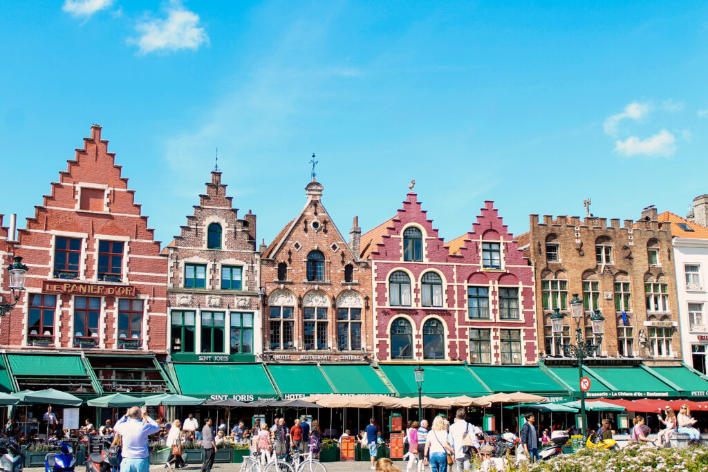 Bruges market square with Flemish guild houses and outdoor café terraces, cycling holiday in Belgium