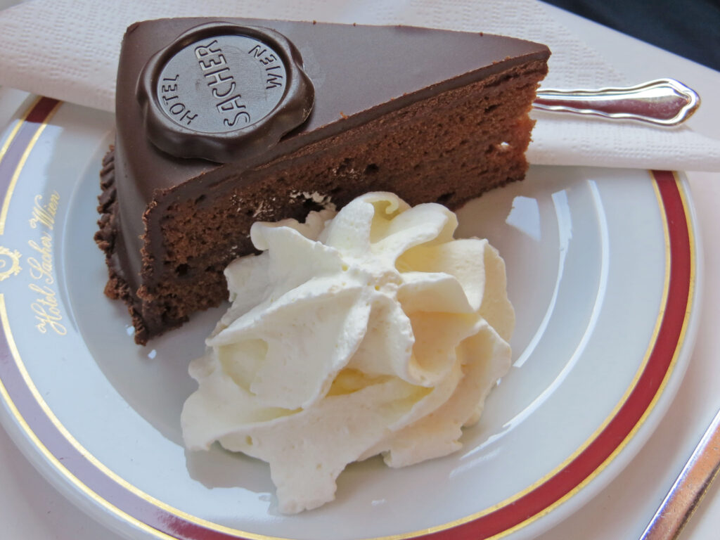 Slice of Viennese Sachertorte with whipped cream served on decorated plate in a historic coffee shop in Vienna