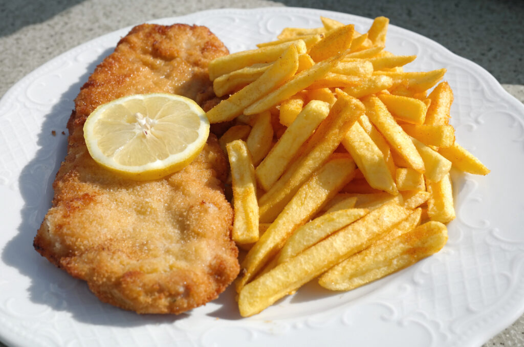 Crispy Wiener Schnitzel with fries and lemon slice: typical dish to enjoy in Vienna