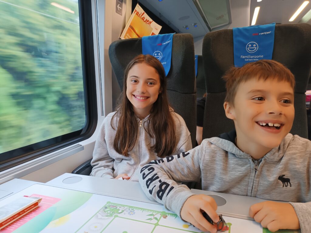 Two children drawing on a cycling route map while travelling by train