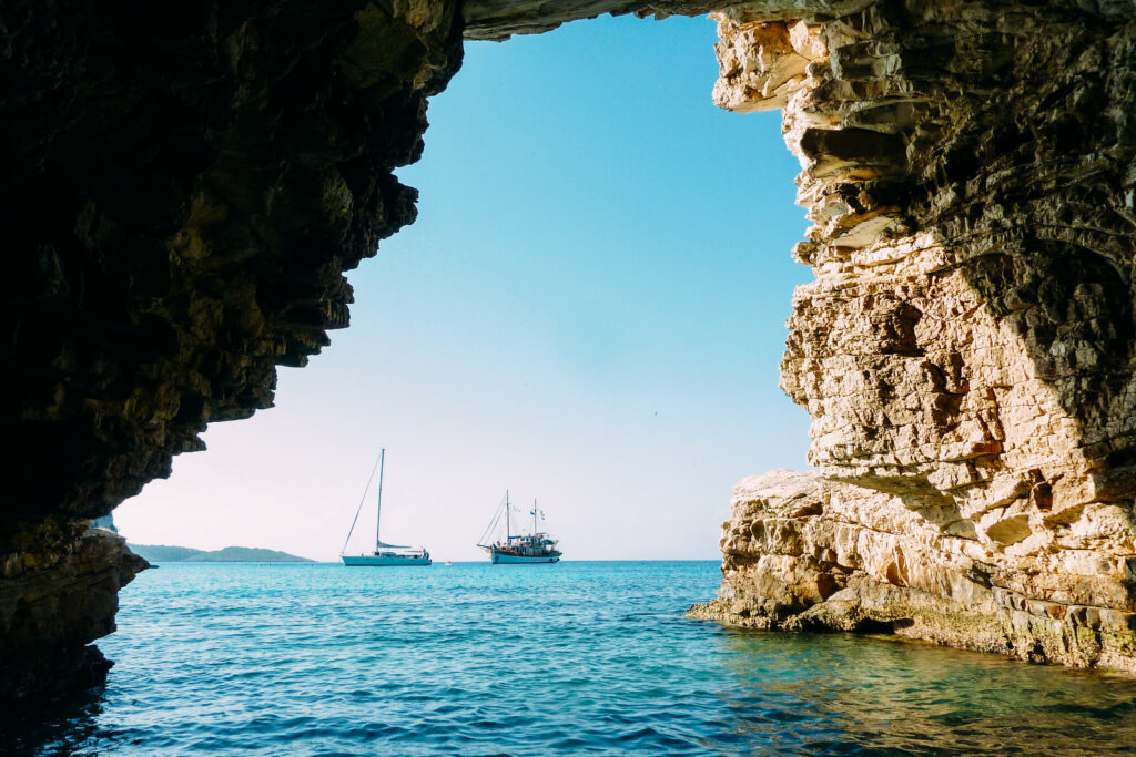 View of sailing boats from a sea cave, bike and boat tour Greece