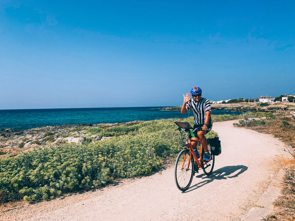 6. Cyclist riding a gravel coastal path  in Puglia with the sea in the background